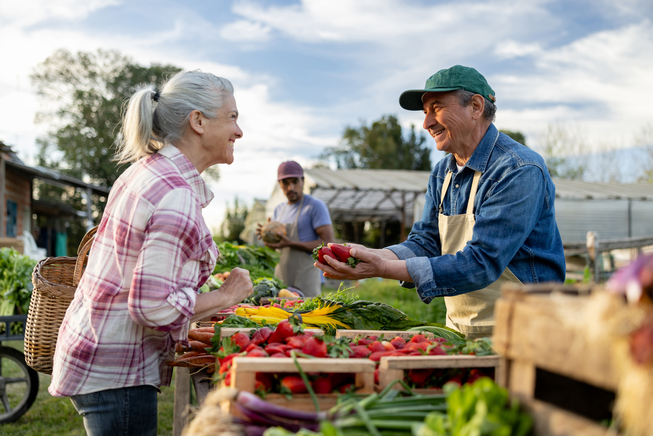 Happy farmer selling organic strawberries to a client at a Farmer’s Market